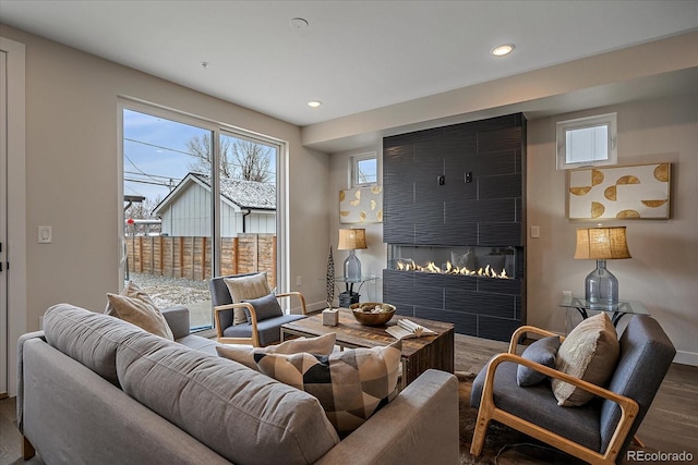 living area with a large fireplace, baseboards, wood finished floors, and recessed lighting