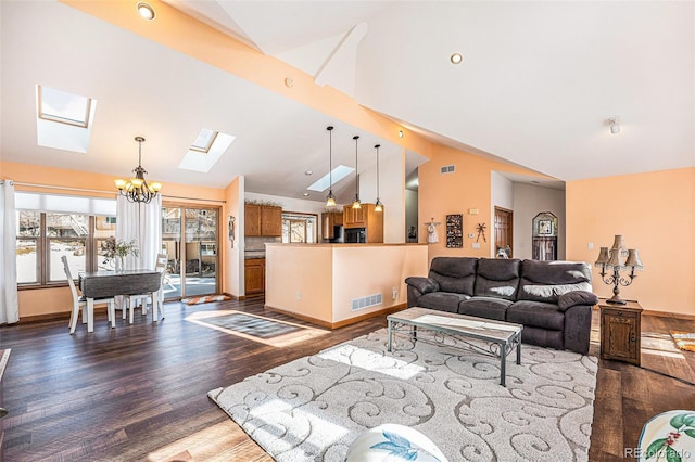 living room featuring an inviting chandelier, vaulted ceiling with skylight, and dark wood-type flooring