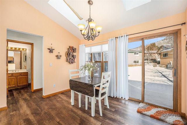 dining room with lofted ceiling with skylight, dark hardwood / wood-style flooring, sink, and a notable chandelier