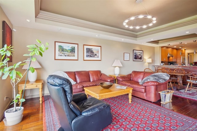 living room with crown molding, wood-type flooring, and a tray ceiling