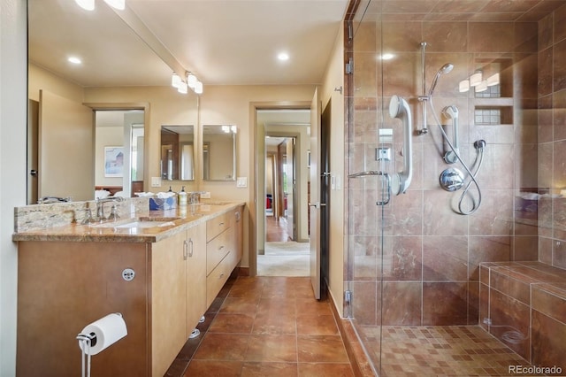 full bath featuring a sink, a stall shower, double vanity, and tile patterned floors