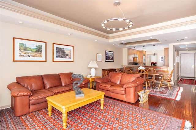 living room with recessed lighting, crown molding, a raised ceiling, and hardwood / wood-style floors