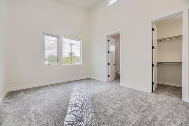 unfurnished bedroom with light colored carpet, connected bathroom, and a spacious closet