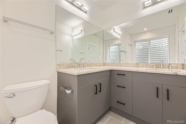 bathroom with tile flooring, double vanity, and toilet