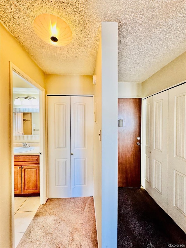 corridor featuring a textured ceiling, carpet floors, and a sink