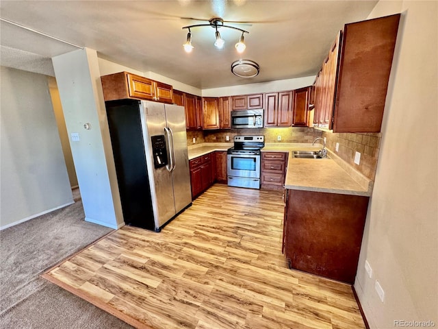 kitchen with baseboards, a sink, decorative backsplash, light countertops, and appliances with stainless steel finishes