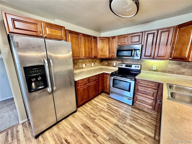 kitchen featuring tasteful backsplash, stainless steel appliances, light countertops, and a sink