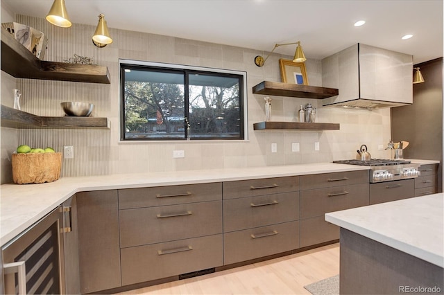 kitchen with hanging light fixtures, decorative backsplash, light wood-type flooring, stainless steel gas stovetop, and wine cooler