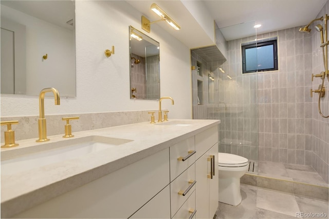 bathroom featuring toilet, a tile shower, and vanity