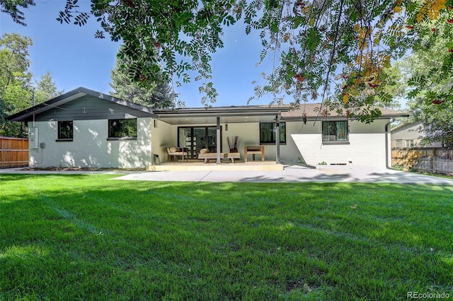 back of property with a yard and a patio area