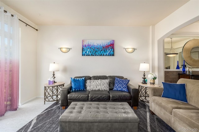 carpeted living room featuring baseboards and arched walkways