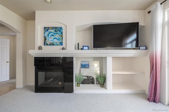 room details with arched walkways, baseboards, carpet flooring, and a tiled fireplace