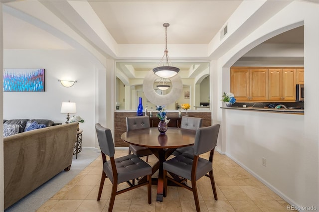 dining space featuring light tile patterned floors, baseboards, visible vents, and a tray ceiling