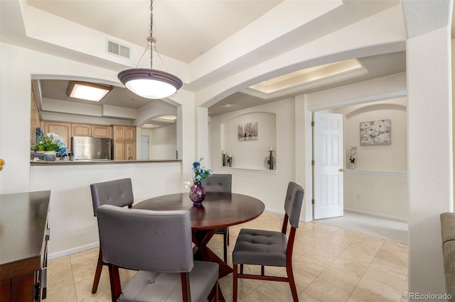 dining room featuring light tile patterned floors, a raised ceiling, visible vents, and baseboards