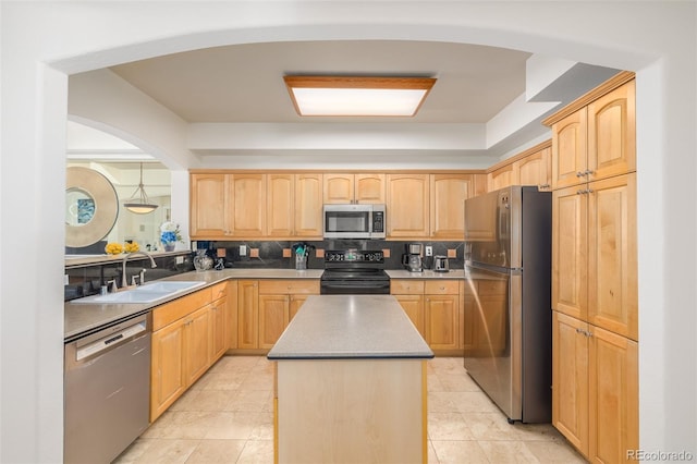 kitchen featuring appliances with stainless steel finishes, a center island, a sink, light brown cabinetry, and backsplash