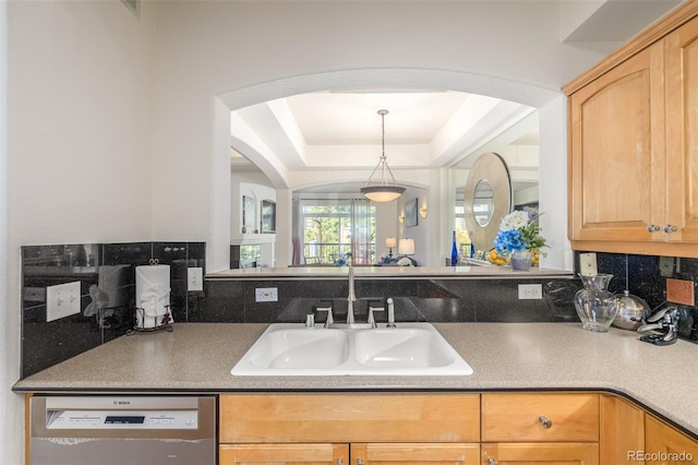 kitchen with tasteful backsplash, a raised ceiling, light brown cabinets, a sink, and dishwasher