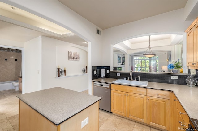 kitchen with a tray ceiling, decorative light fixtures, stainless steel dishwasher, a kitchen island, and a sink