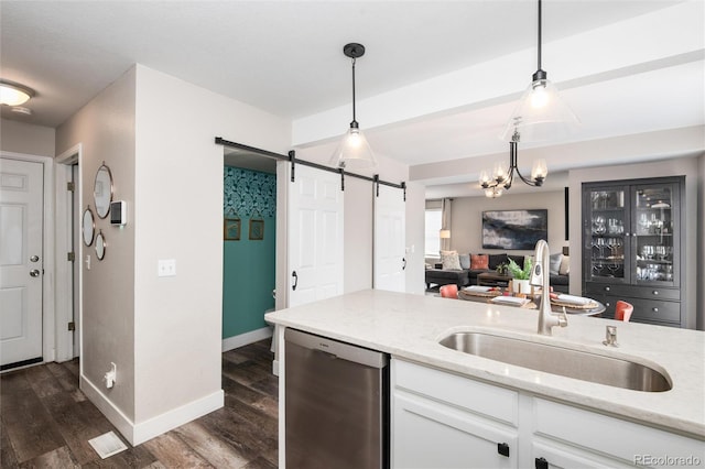 kitchen with dishwasher, pendant lighting, a barn door, white cabinets, and sink