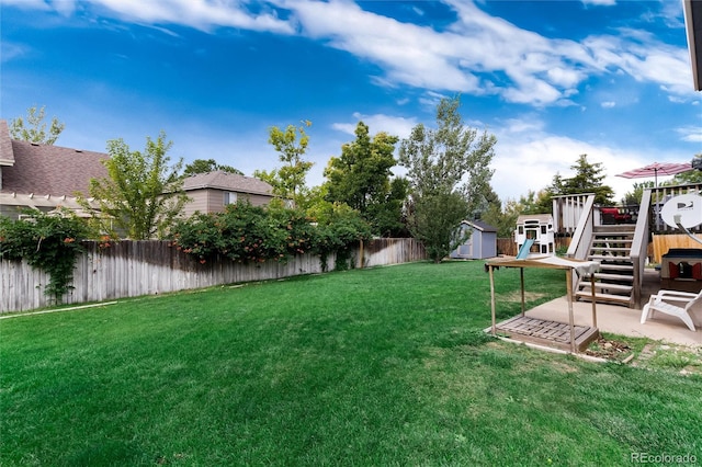 view of yard featuring a deck, a patio area, and a storage shed