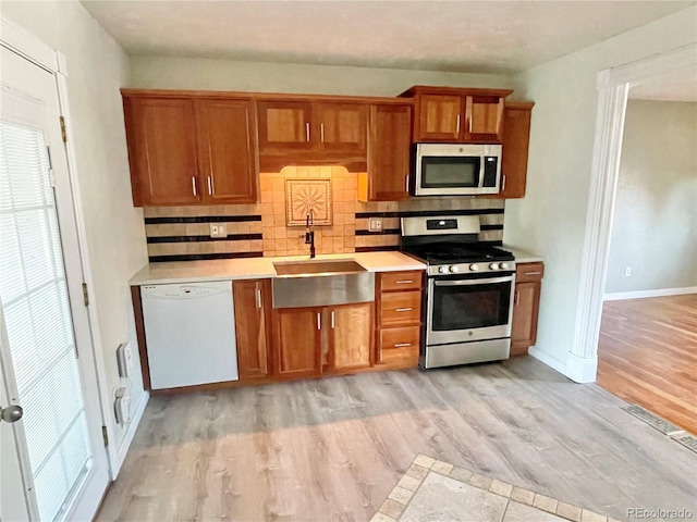 kitchen featuring decorative backsplash, sink, light hardwood / wood-style floors, and appliances with stainless steel finishes