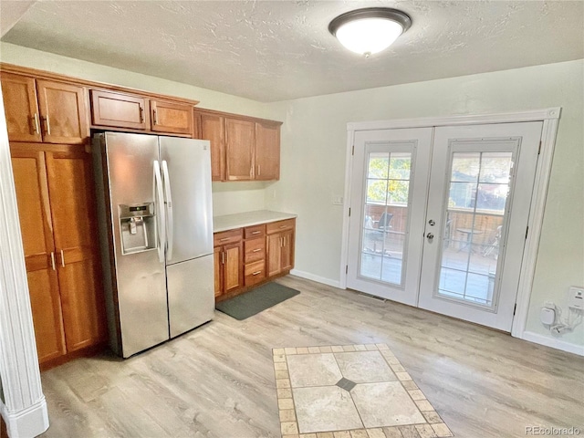 kitchen featuring a textured ceiling, french doors, stainless steel refrigerator with ice dispenser, and light hardwood / wood-style flooring