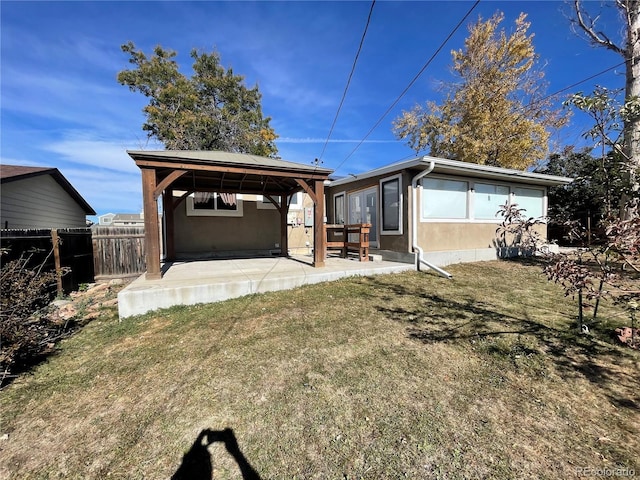 back of property with a gazebo, a lawn, and a patio