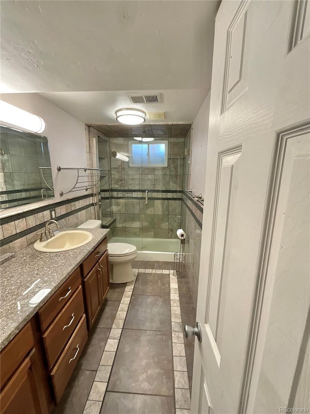 bathroom featuring decorative backsplash, vanity, a shower with door, tile patterned flooring, and toilet