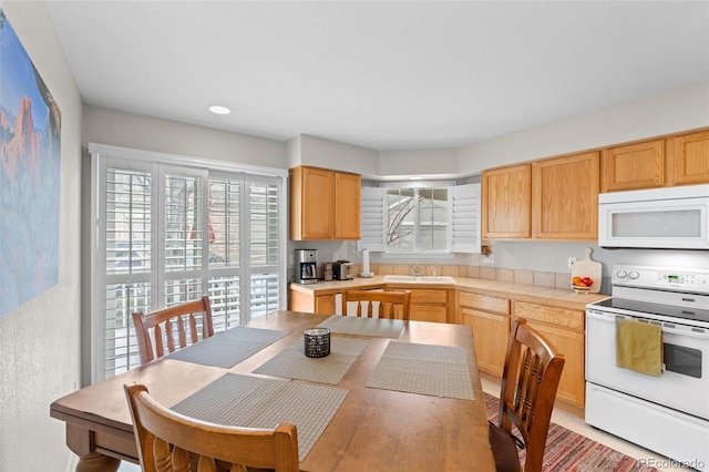 kitchen with white appliances, light brown cabinets, and a sink