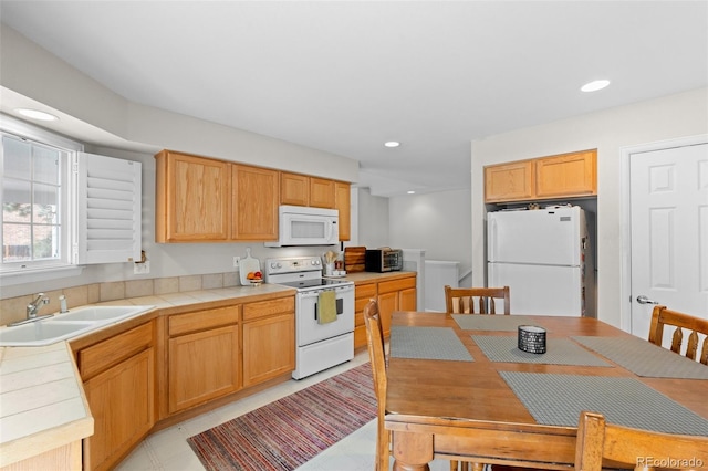 kitchen featuring tile counters, recessed lighting, white appliances, and a sink