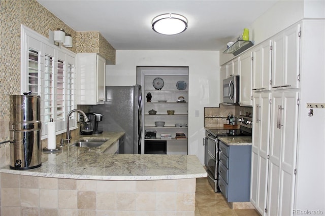 kitchen with light stone counters, tasteful backsplash, a sink, stainless steel appliances, and white cabinetry