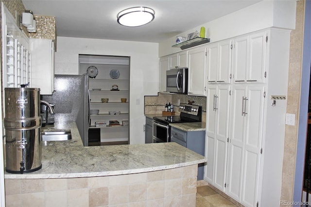 kitchen with stainless steel appliances, a peninsula, a sink, and backsplash