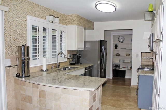 kitchen with white cabinets, dishwasher, light stone counters, and a sink