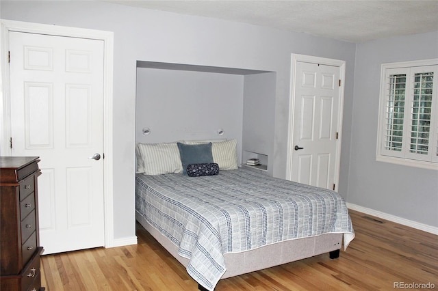 bedroom featuring baseboards, visible vents, and light wood finished floors
