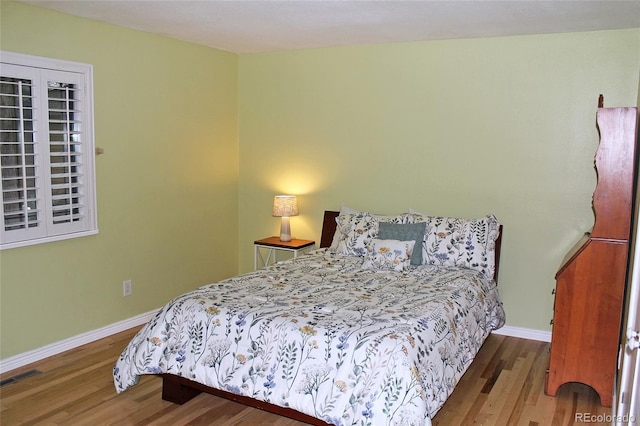 bedroom with baseboards, wood finished floors, and visible vents