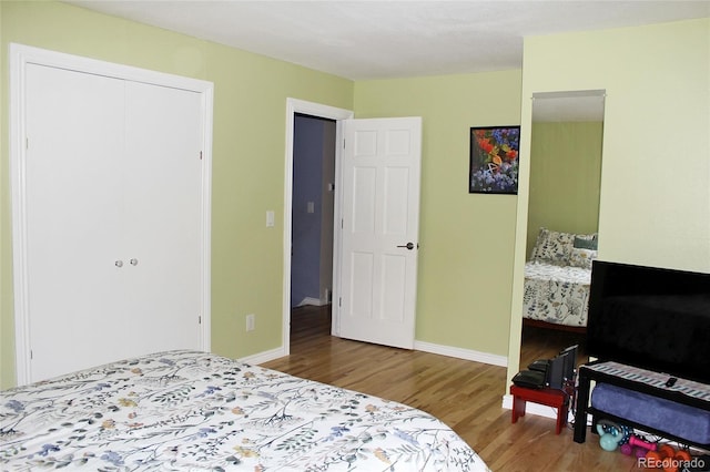 bedroom featuring baseboards, wood finished floors, and a closet
