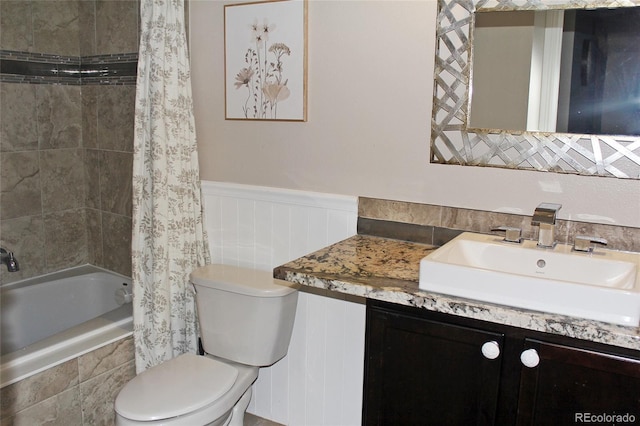 full bathroom featuring tiled shower / bath combo, a wainscoted wall, vanity, and toilet