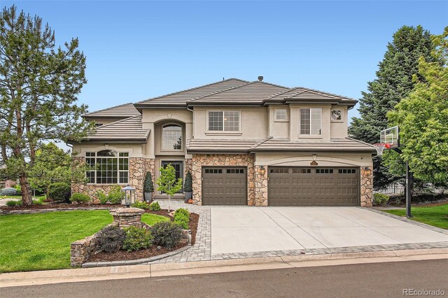 9445 Aspen Hill Cir, Lone Tree, CO 80124 - view of front of property with stone siding, a garage, driveway, stucco siding, and a front yard