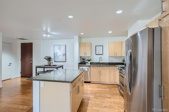 kitchen featuring appliances with stainless steel finishes, light brown cabinetry, sink, and a kitchen island