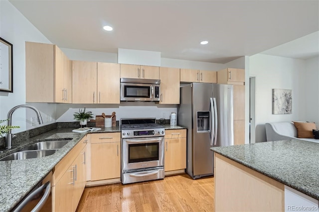 kitchen featuring appliances with stainless steel finishes, sink, light brown cabinets, and dark stone counters