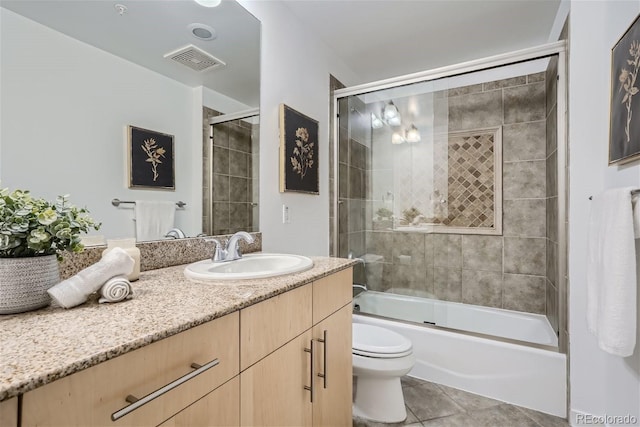 full bathroom featuring vanity, tile patterned floors, shower / bath combination with glass door, and toilet