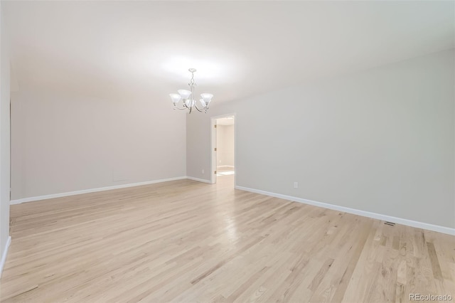 spare room with light wood-type flooring and a chandelier