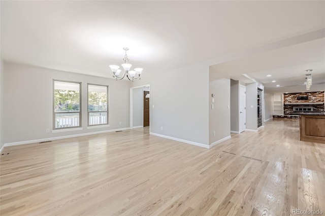 unfurnished living room featuring light hardwood / wood-style flooring and an inviting chandelier