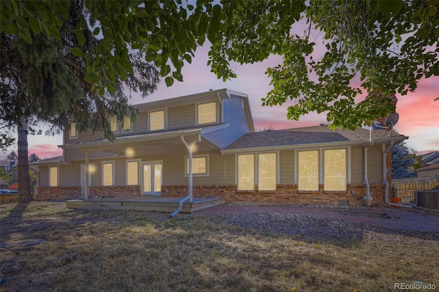 back house at dusk featuring central air condition unit, a patio area, and a yard