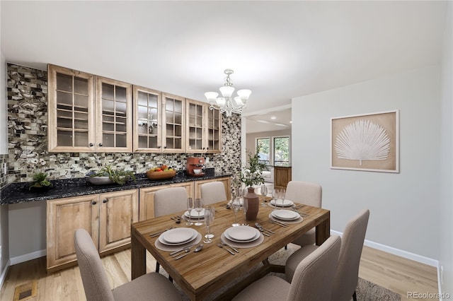 dining area with light hardwood / wood-style floors and a chandelier