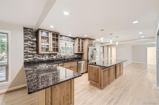 kitchen featuring appliances with stainless steel finishes, hanging light fixtures, sink, and a kitchen island