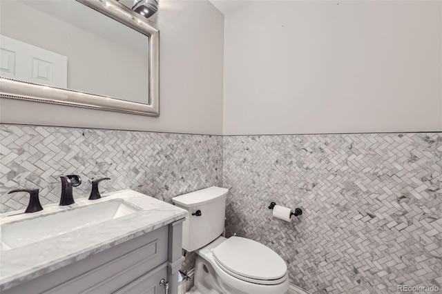 bathroom with toilet, vanity, and tile walls