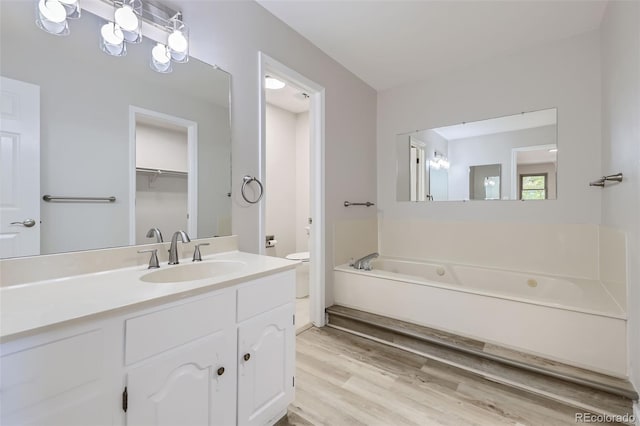 bathroom with a bathtub, vanity, hardwood / wood-style flooring, and toilet