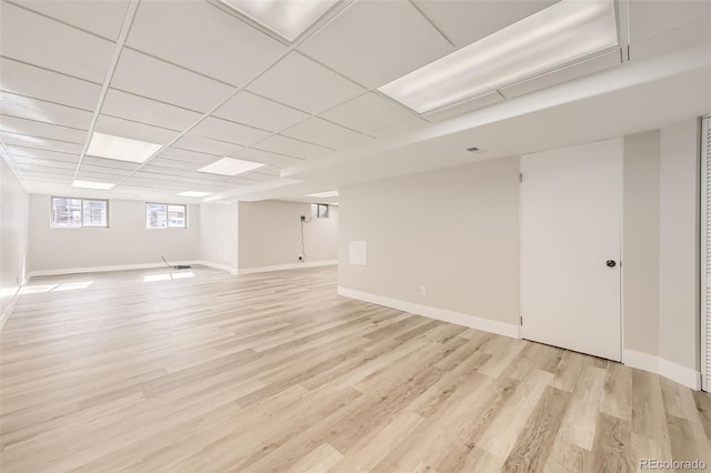 basement featuring a drop ceiling and light hardwood / wood-style floors