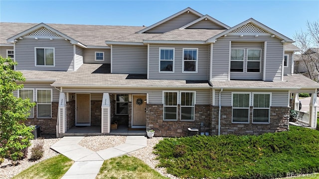 9758 Laredo St Unit 22D, Commerce City, CO 80022 - view of front of house featuring stone siding, a shingled roof, and a porch