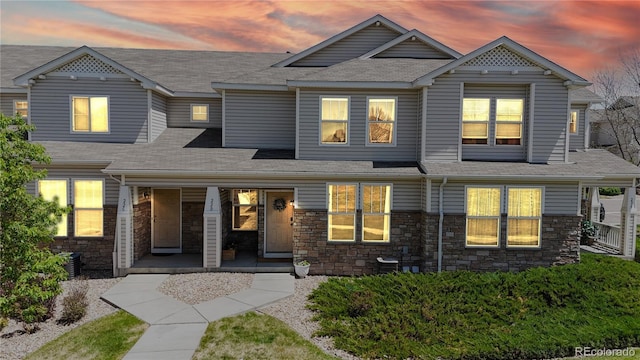 9758 Laredo St Unit 22D, Commerce City, CO 80022 - view of front of house with a porch, roof with shingles, and stone siding